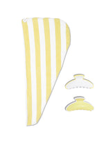 Yellow and white striped towel with two hair clips on a white background