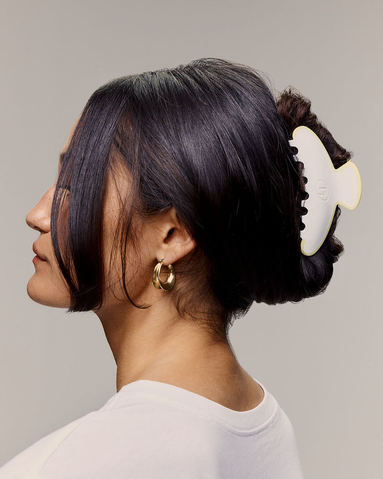Woman with a hair clip in her dark hair against a gray background