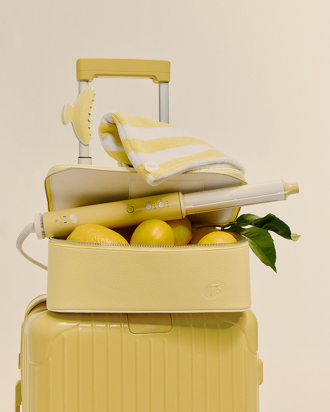 Yellow suitcase with a hair straightener, towel, and lemons on a beige background