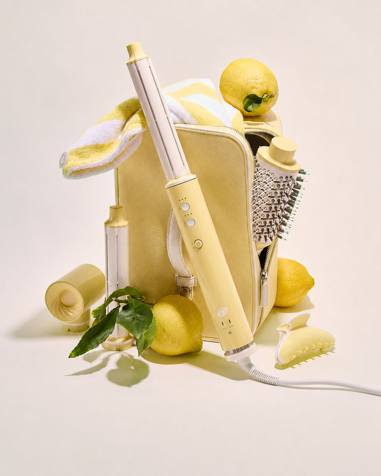 Yellow hair styling tools with lemons and a brush on a light background