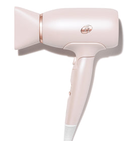 Pink hair dryer with rose gold accents on a white background